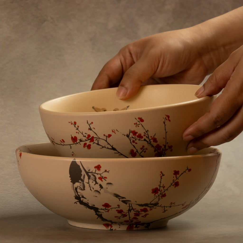 Hands stacking Sakura salad bowls with cherry blossom design