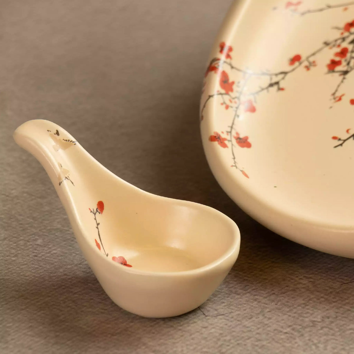 Sakura ceramic spoon rest beside oval platter with blossom art