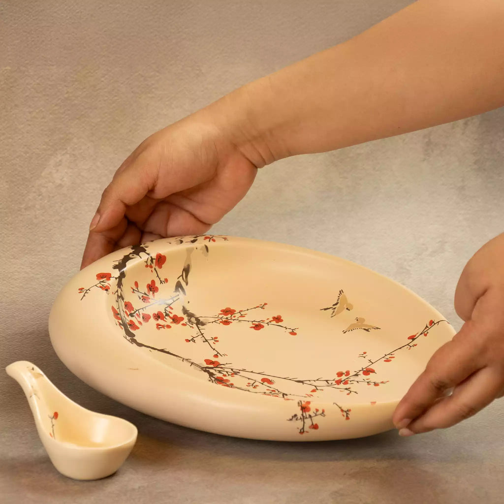 Hands holding Sakura oval platter with ceramic spoon beside