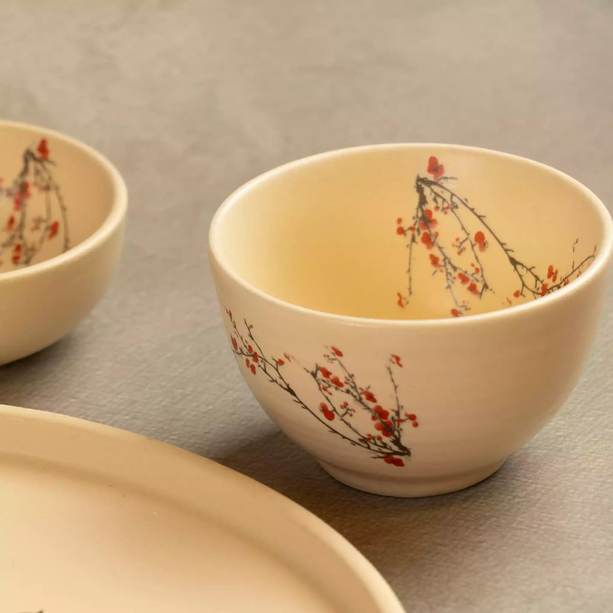 Sakura cherry blossom bowl beside dinner plate in beige ceramic