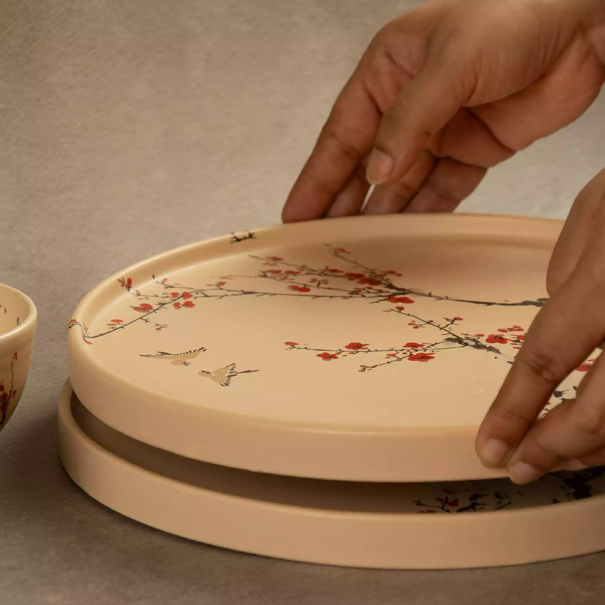 Hand lifting Sakura dinner plate from stack, cherry blossom design