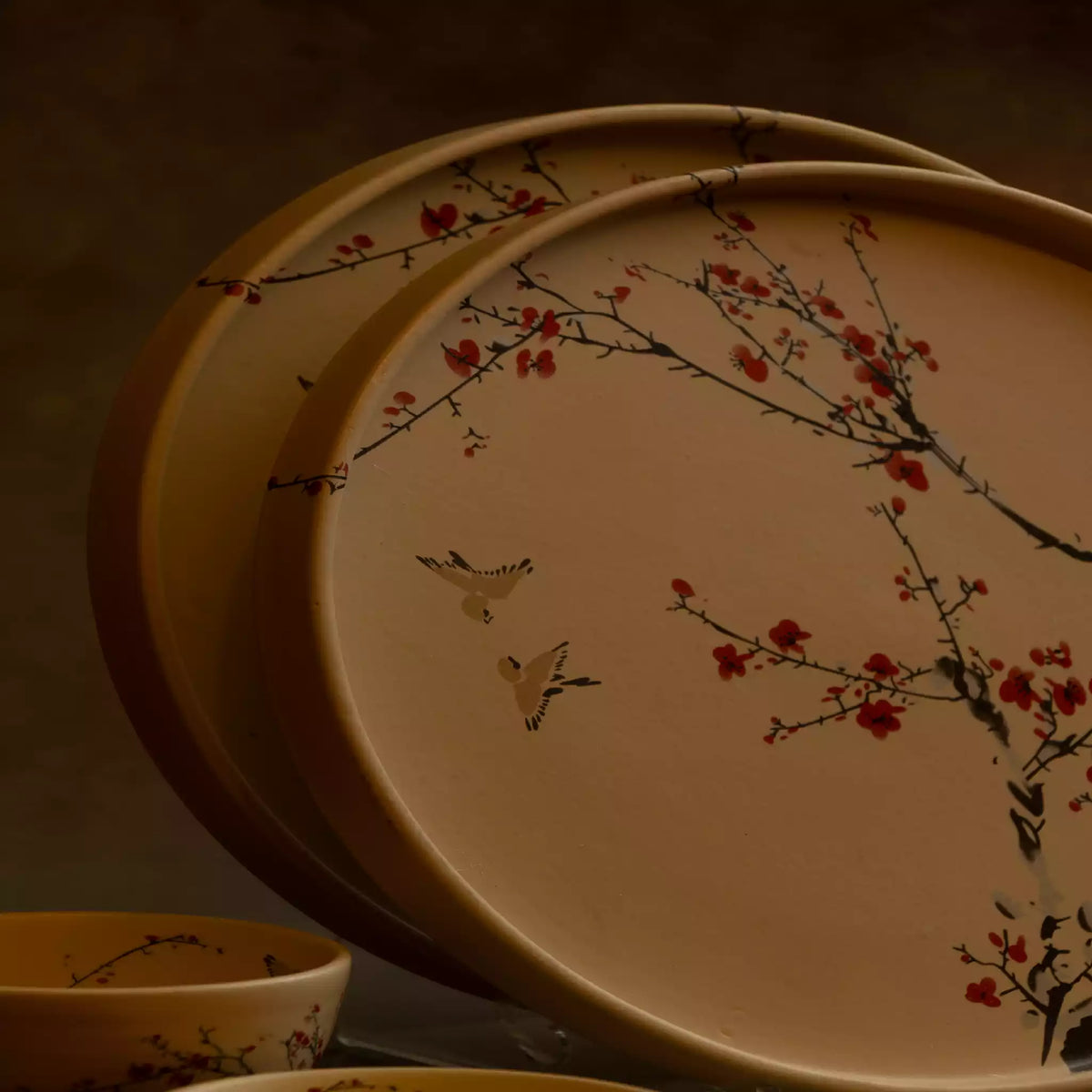 Sakura dinner plates stacked with bowl, warm-lit blossom ceramic