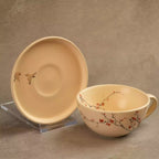 Sakura tea cup beside upright saucer showing blossom motif
