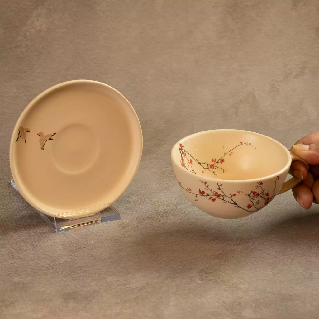 Sakura tea cup held beside matching saucer with blossom detail