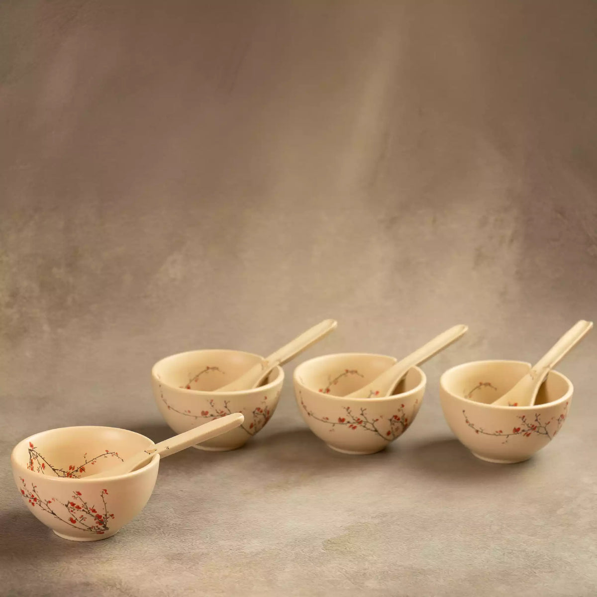 Three Sakura soup bowls with spoons lined up on grey backdrop
