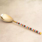 Rainbow gold serving spoon angled view with striped handle