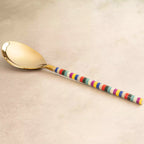Rainbow serving spoon with multicolour handle on beige backdrop
