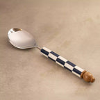 Blue checkers serving spoon angled on beige backdrop