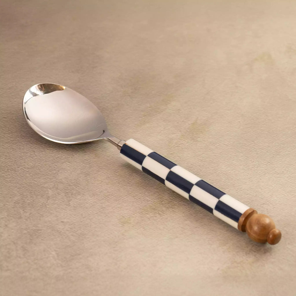 Blue checkers serving spoon angled on beige backdrop