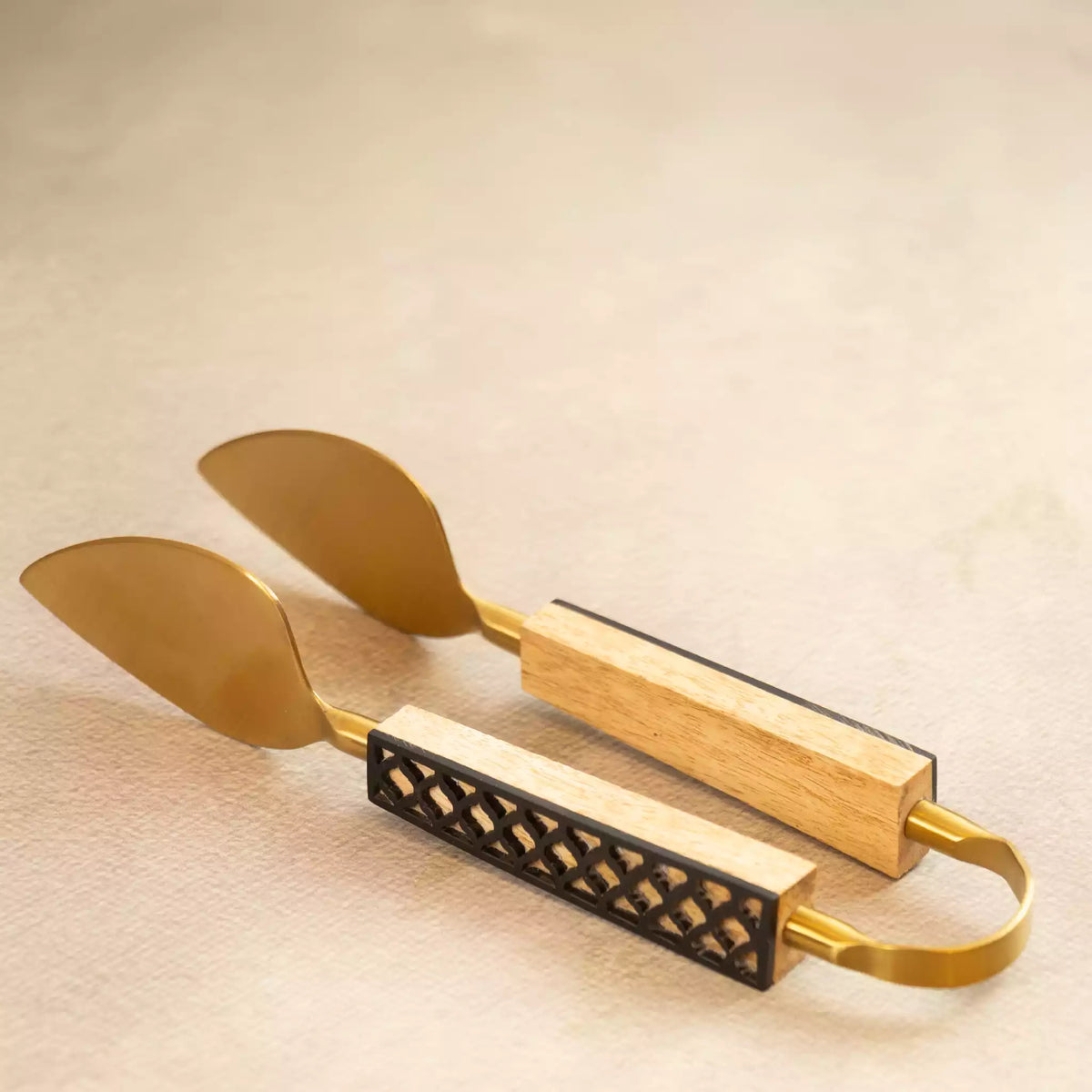Carved brass tongs and two spatulas with black textured handle detail