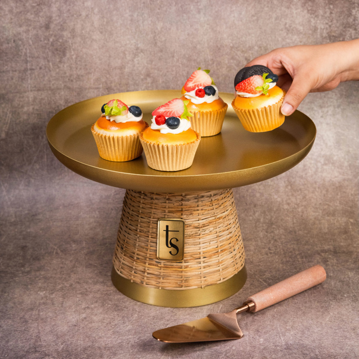 Hand placing cupcakes on wicker and metal cake stand