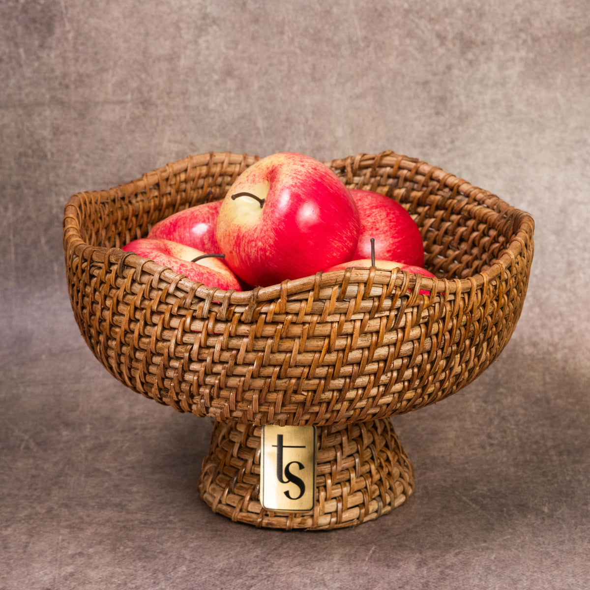 Cane fruit bowl filled with red apples front view