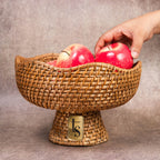 Hand placing apple into woven cane fruit bowl