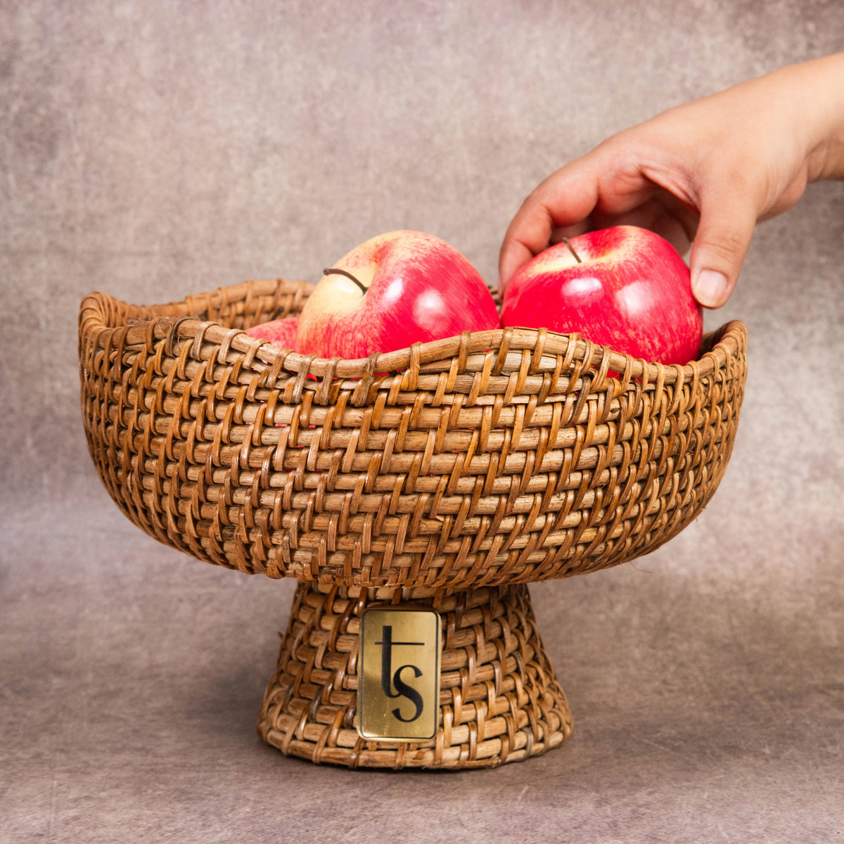 Hand placing apple into woven cane fruit bowl