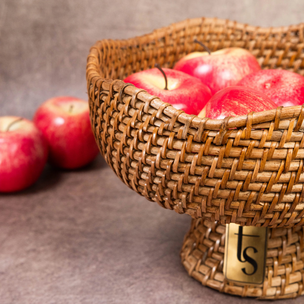 Cane fruit bowl overflowing with red apples